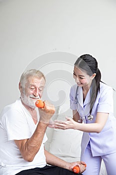 Senior retirement man doing dumbbell fitness training with  physiotherapist