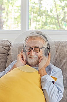 Senior retirement man listen to music using headphone feeling happy in his home