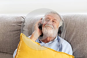 Senior retirement man listen to music using headphone feeling happy in his home