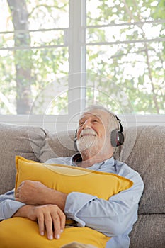 Senior retirement man listen to music using headphone feeling happy in his home