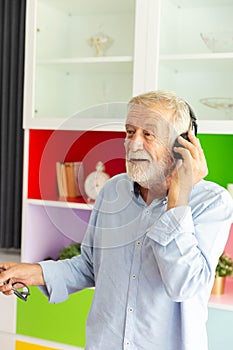 Senior retirement man listen to music using headphone feeling happy in his home