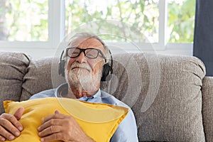 Senior retirement man listen to music using headphone feeling happy in his home