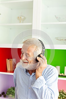 Senior retirement man listen to music using headphone feeling happy in his home