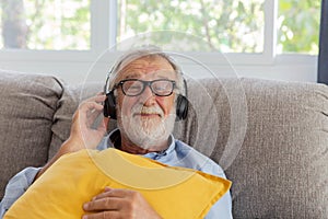 Senior retirement man listen to music using headphone feeling happy in his home