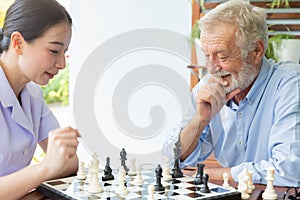 Senior retirement man playing chess with nurse at home