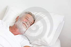 Senior retirement man sleeping happily in his white blanket bed