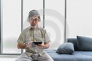 Senior retirement man wear glasses with headphones and listening music. Lifestyle after retire of elderly