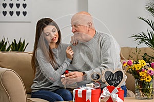 Senior rich man proposing to young woman at home. Marriage of convenience