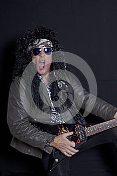 Senior rock guitarist performing over black background