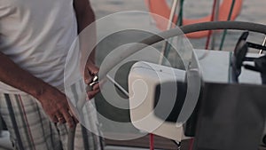 Senior sailor standing behind a steering wheel on the sailboard. Man steers the ship in open sea alone.