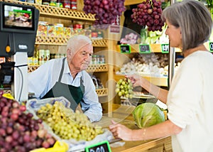 Senior salesman serving woman customer in greengrocer