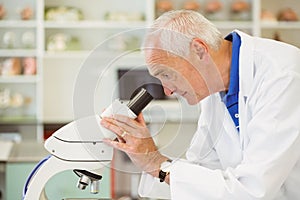 Senior scientist looking through microscope