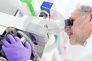 Senior scientist microscoping in lab.