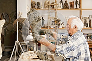 Senior sculptor making sculpture sideview