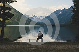 Senior is seating alone on the beach bench in overcast weather