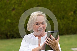 Senior serene woman using a black tablet PC