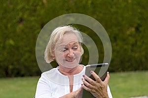 Senior serene woman using a black tablet PC