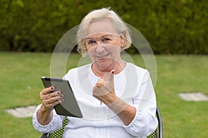 Senior serene woman using a black tablet PC