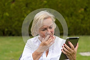 Senior serene woman using a black tablet PC