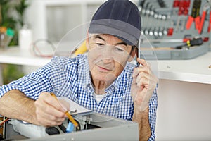 Senior serviceman using telephone while testing appliance