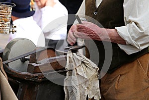 Senior while sharpens knife in old grindstone