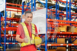 senior shipping company worker giving thumb up inside warehouse