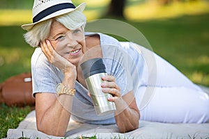 senior smiley woman drinking tea or coffee outdoors