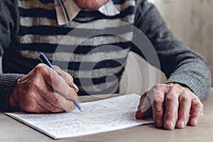 Senior solves sudoku or a crossword puzzle to slow the progressi