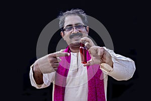 Senior south asian man holding an cosmetics or showing products pointing to the side with finger