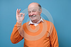 Senior spanish man showing OK sign approving choice