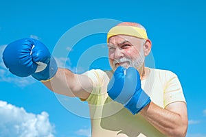 Senior sportive man in boxing stance doing exercises with boxing gloves. Active leisure. Best cardio workout.