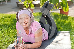 Senior sportive woman lying on mat sunny