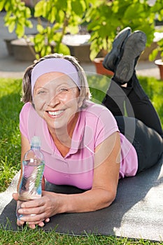 Senior sportive woman lying on mat sunny