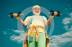 Senior sportman exercising with lifting dumbbell on blue sky background. Isolated, copy space. Senior man in gym working