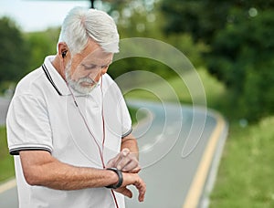 Senior sportsman looking on handwatch during morning scamper.
