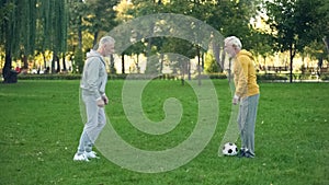 Senior sportsmen playing football on weekend in park, active leisure, friendship