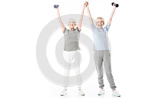 Senior sportswomen with arms up holding dumbbell