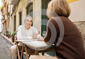 Senior Spouses Having Date Traveling Sitting At Table In Cafe