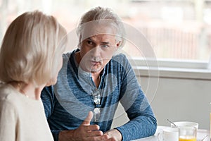 Senior spouses talking sitting together at table focus on husband