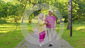 Senior stylish pensioners couple grandmother grandfather walking, enjoying time together in park