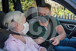 Senior and sun with face masks in the car