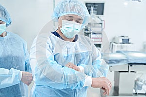 Senior surgeon putting on uniform for operation