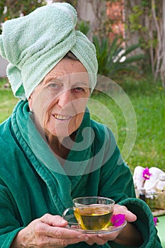 A senior takes her cup of tisane in an open air spa studio