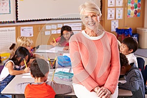 Senior teacher in classroom with elementary school kids