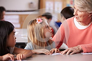 Senior teacher helping pupils in elementary school lesson