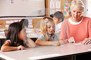 Senior teacher helping pupils in elementary school lesson