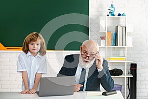 Senior teacher and pupil in classroom. Education concept. Boy elementary school. Old and Young. Grandfather and child