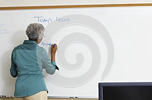 Senior Teacher Writing On Whiteboard