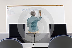 Senior Teacher Writing On Whiteboard