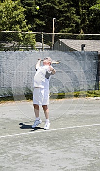 Senior tennis player serving ball